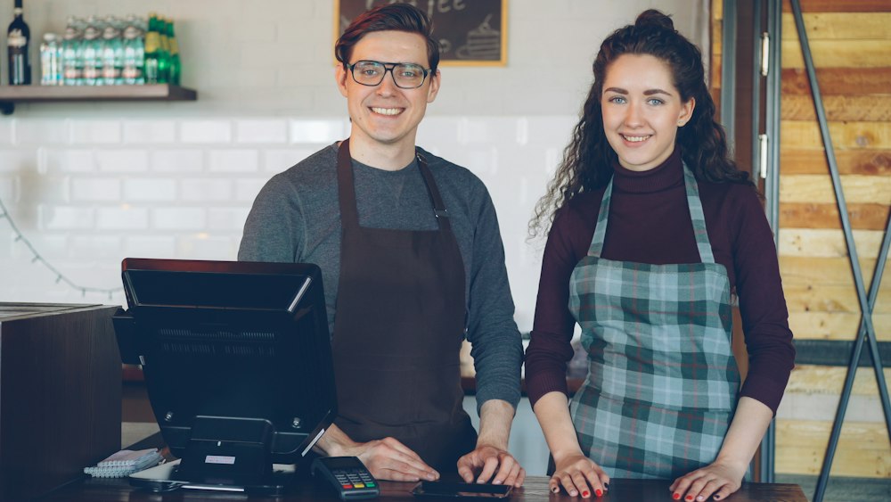 Two café owners smiling behind their counter